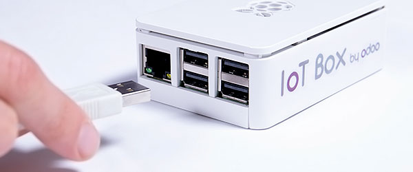 A hand connecting a USB plug to the Odoo IoT box